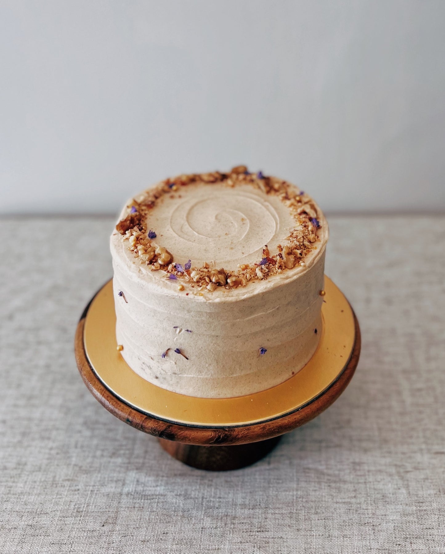 whole carrot walnut cake on wooden stand with textured frosting Singapore